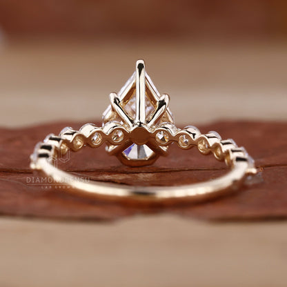 Detailed view of a yellow gold engagement ring with a spear cut diamond and pave diamonds.