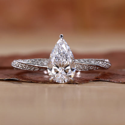 Close-up of a pear shaped diamond ring featuring twisted diamond pave